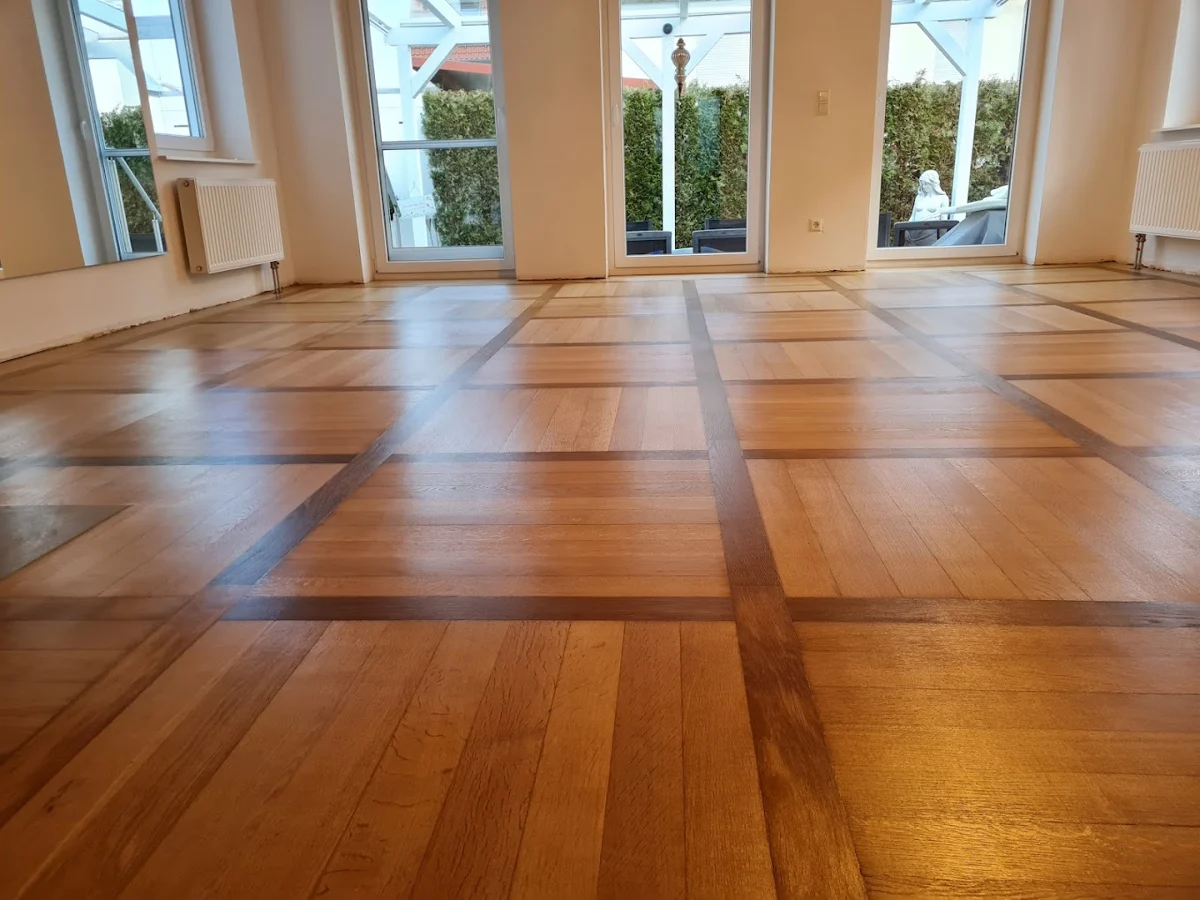 Holzboden mit geometrischem Verlegemuster in einem hellen Raum.