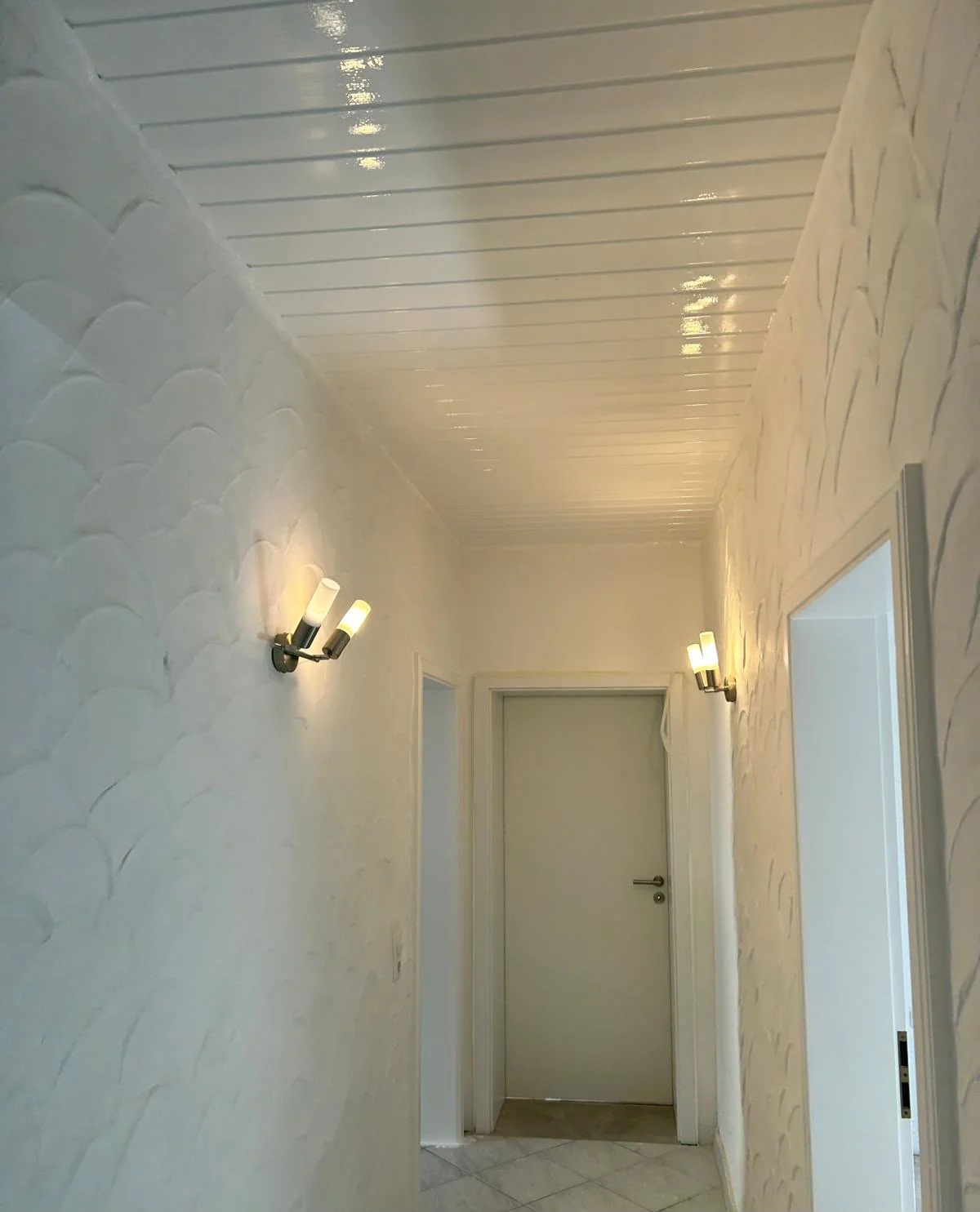Heller Flur mit strukturierten weißen Wänden und weißer Decke.